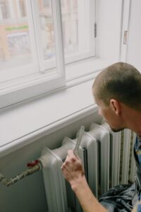 Mann lackiert Heizkörper unter Fensterbank