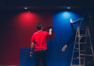 Zwei Menschen streichen Wand in blau und rot