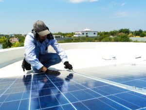 Mann reinigt Solarzellen einer Photovoltaik Anlage auf Dach