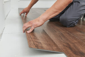 Tischlerarbeiter, der Vinylbodenfliesen in Holzdekoration im Innenbereich installiert