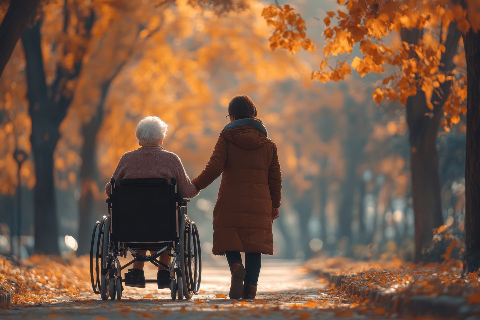 Seniorin im Rollstuhl bei Herbstspaziergang mit Pflegerin