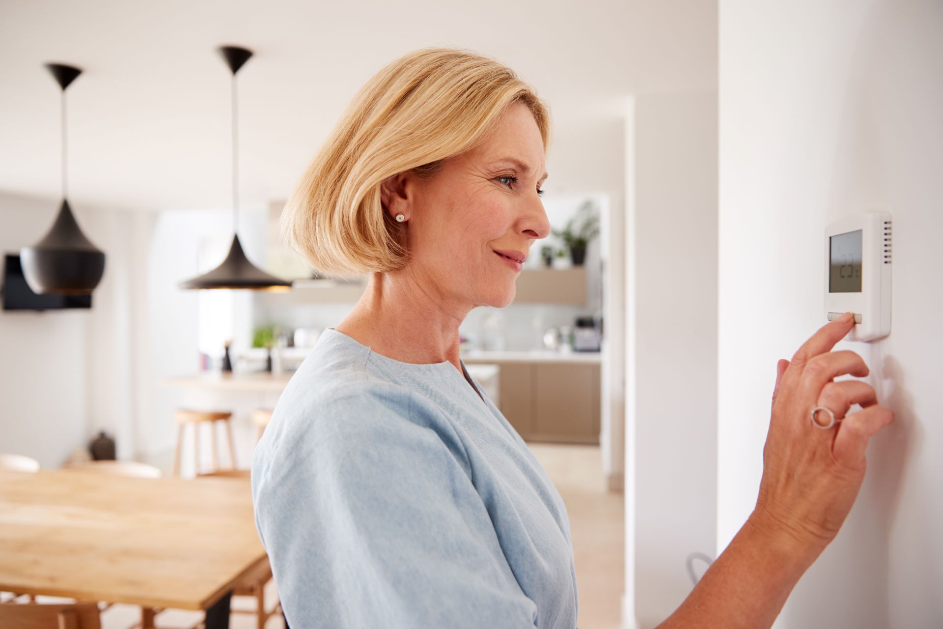 Frau stellt Thermostat für Fußbodenheizung ein.