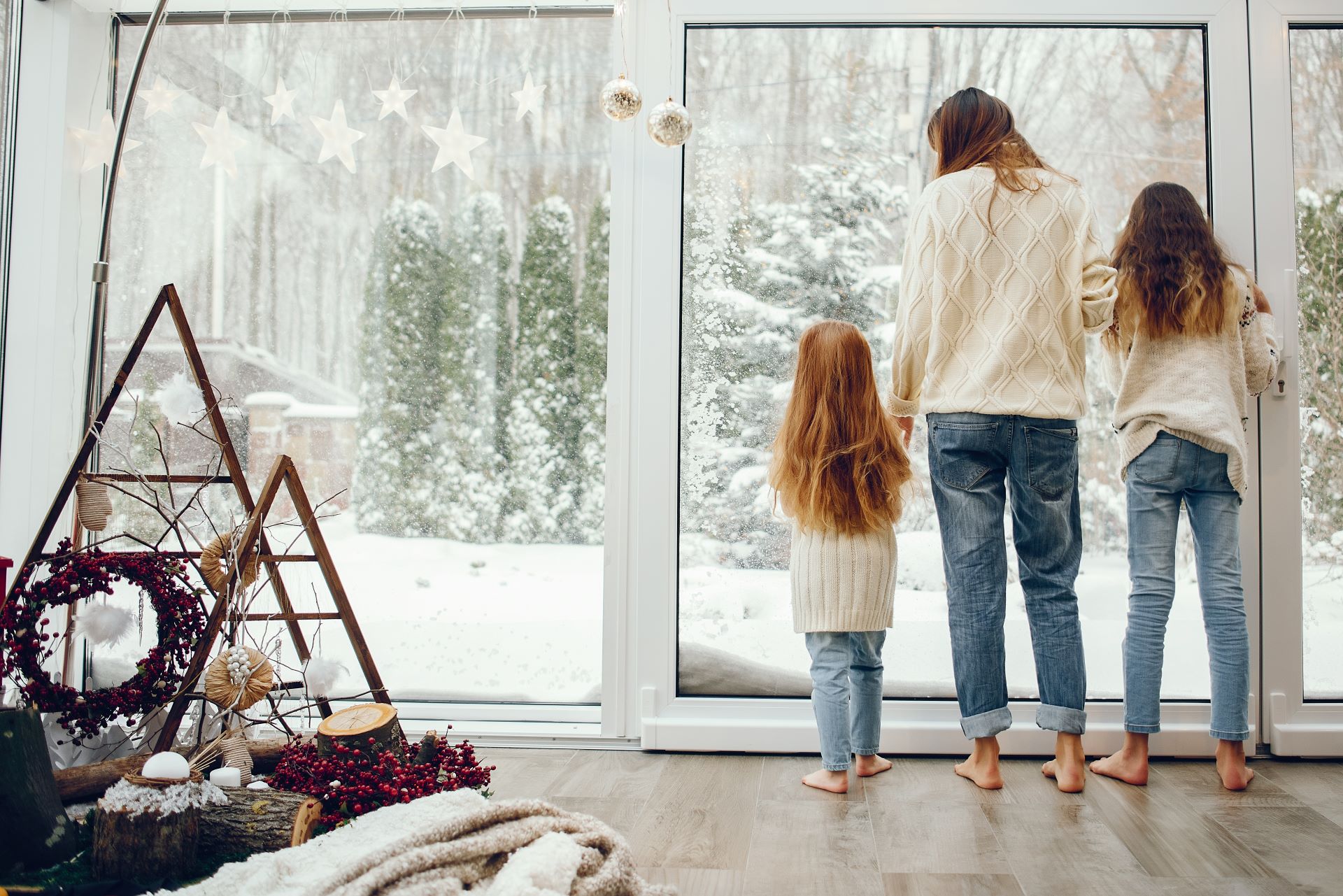 Familie blickt aus Fenster auf verschneiten Garten.